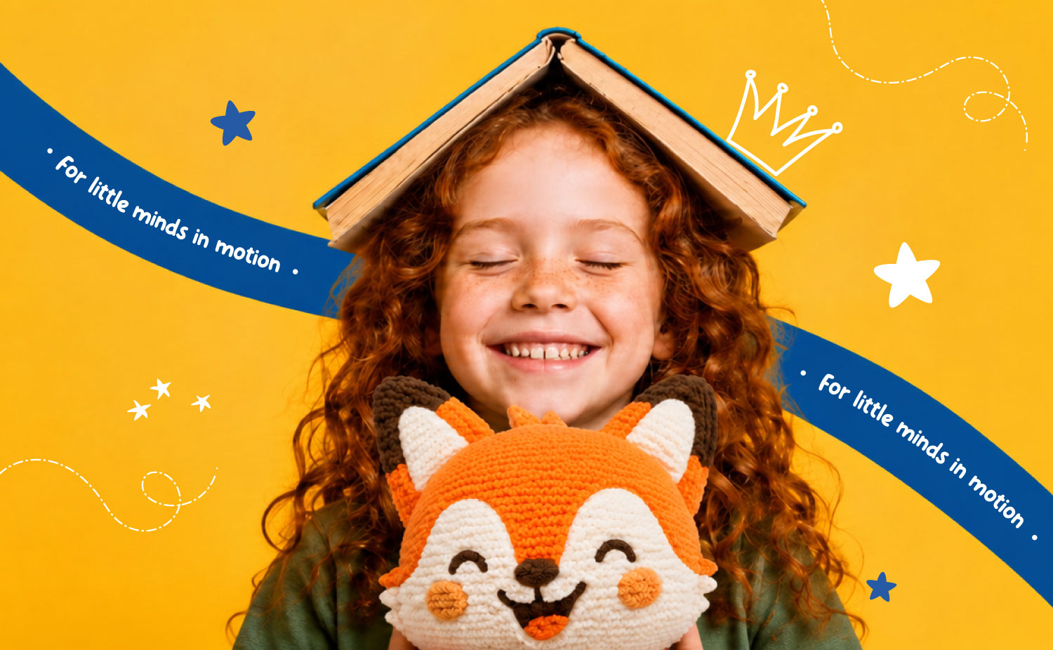 A smiling girl with an open book on her head, hugging a Lou the fox plush